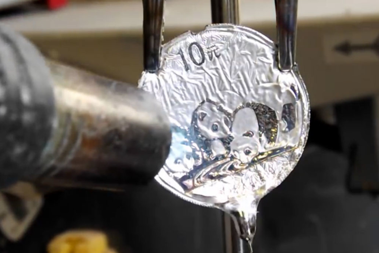 Gefälschter Silberpanda unter einer Heißluftpistole